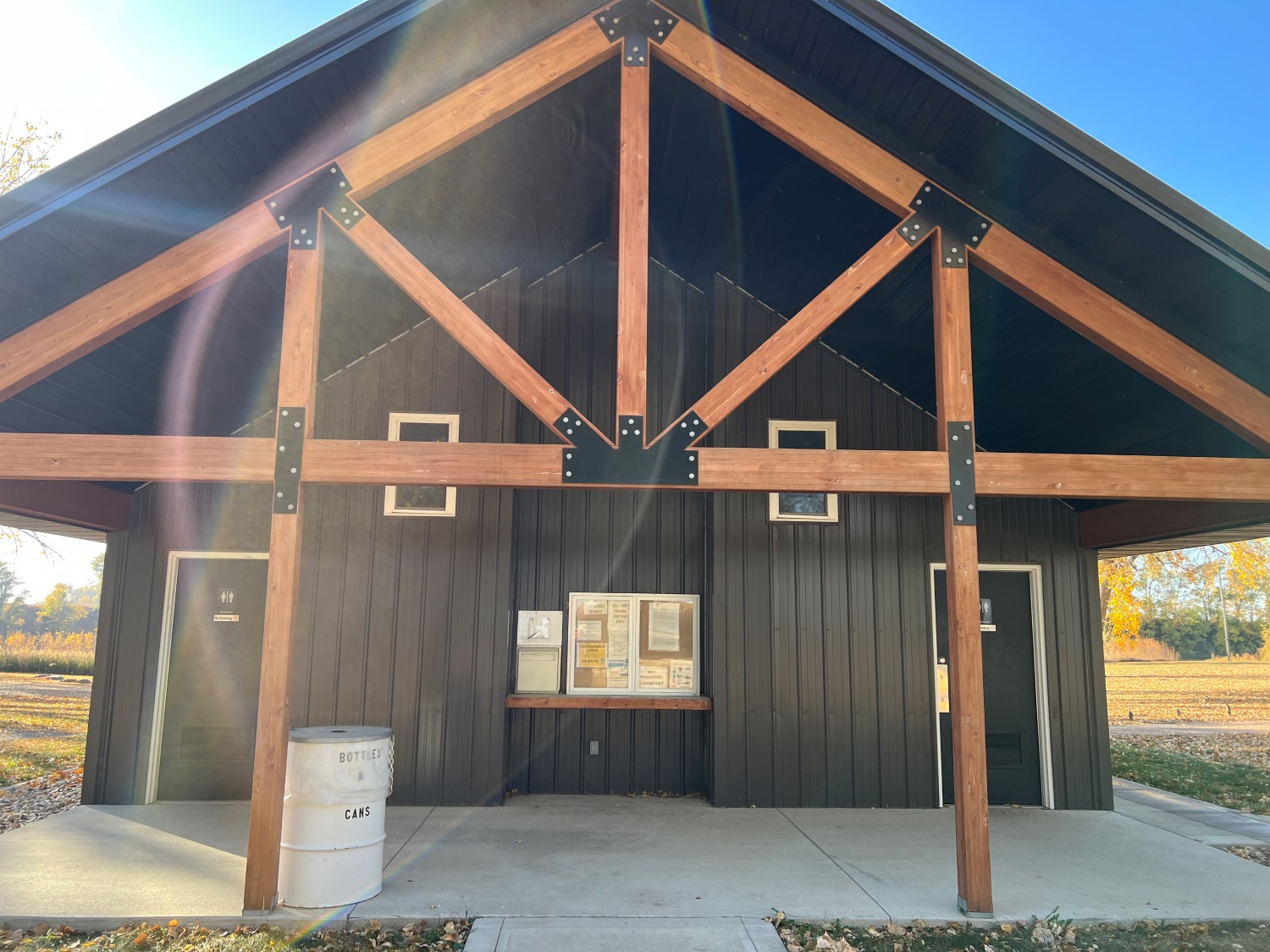 A black building with wood accents and a gabled roof stands in sunlight.